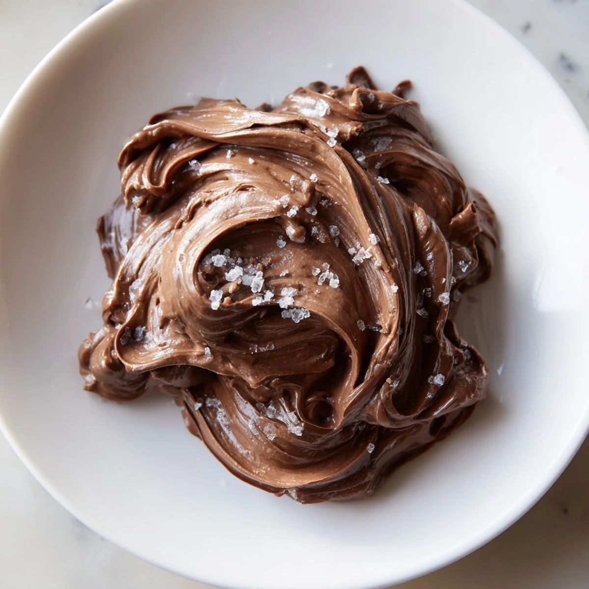 Smooth, glossy dark chocolate spread, perfect for toast, with swirls and a rich aroma.