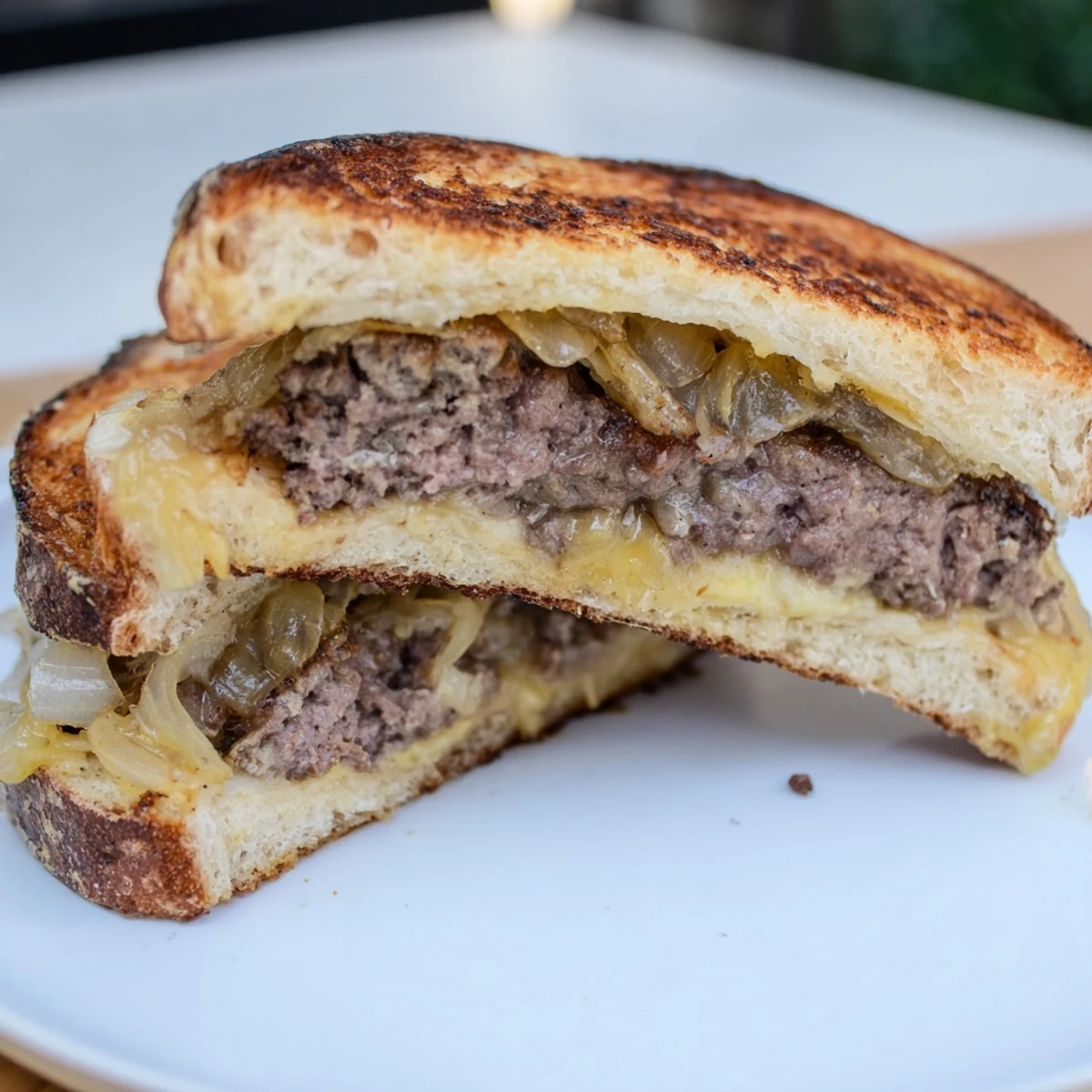 A close-up of a stacked beef patty melt: savory beef, cheese, and rye bread ready to eat.