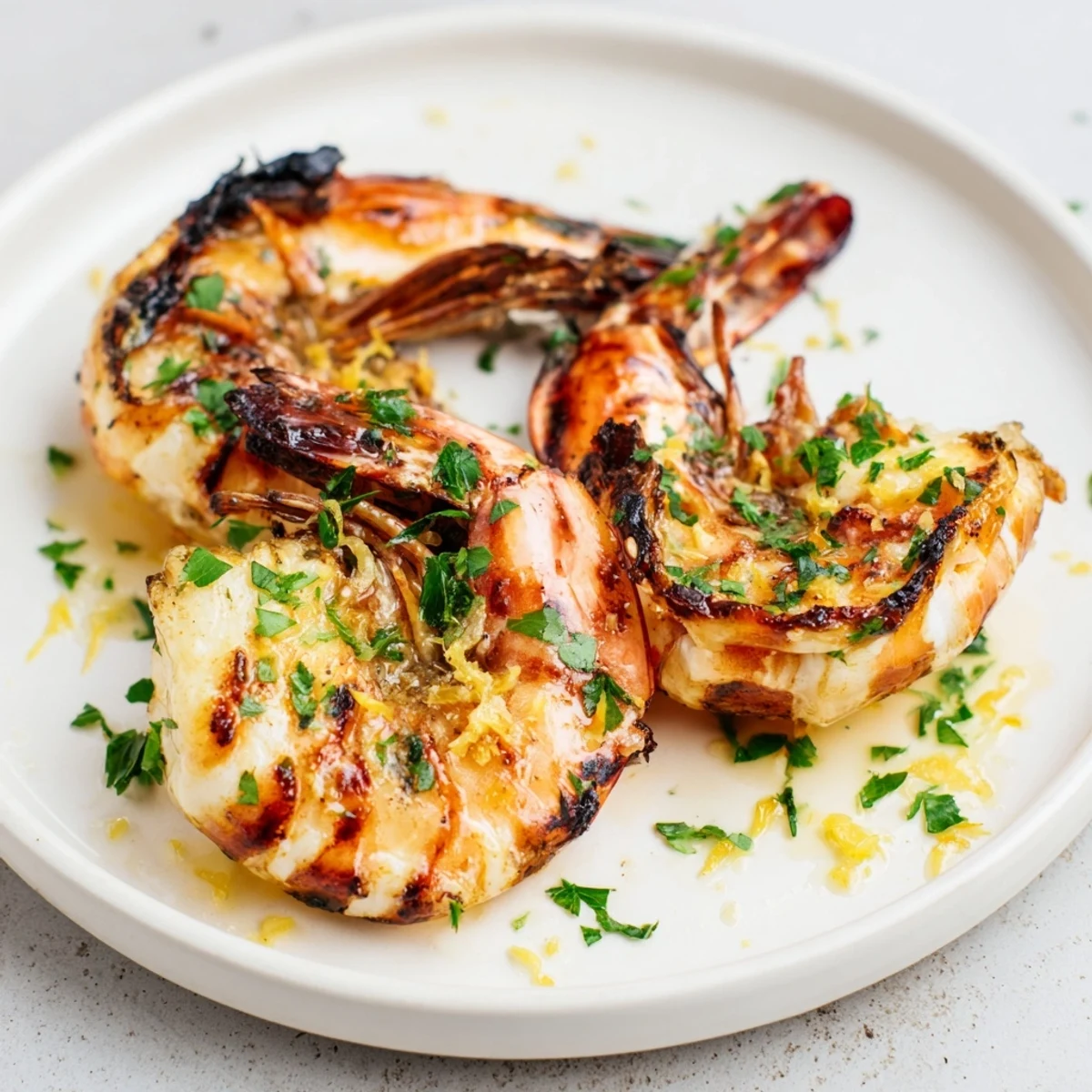 Juicy grilled shrimp glistening after cooking, served with fresh parsley and bright lemon wedges.