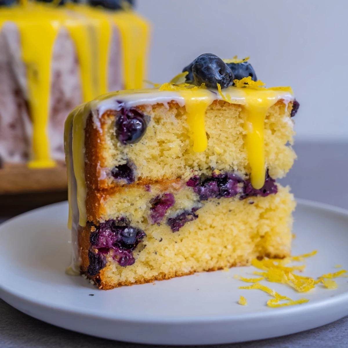 Imagine a close-up of the delicious Lemon and Blueberry Drizzle Cake, ready for tea, covered in drizzle.