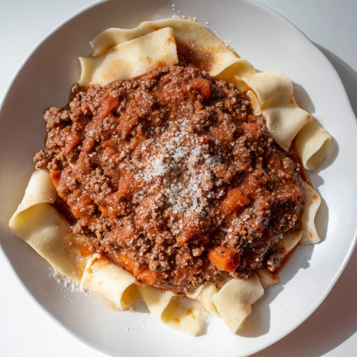 Hearty Beef Bolognese with fresh pasta, Parmesan, and a glistening, flavorful meat sauce.