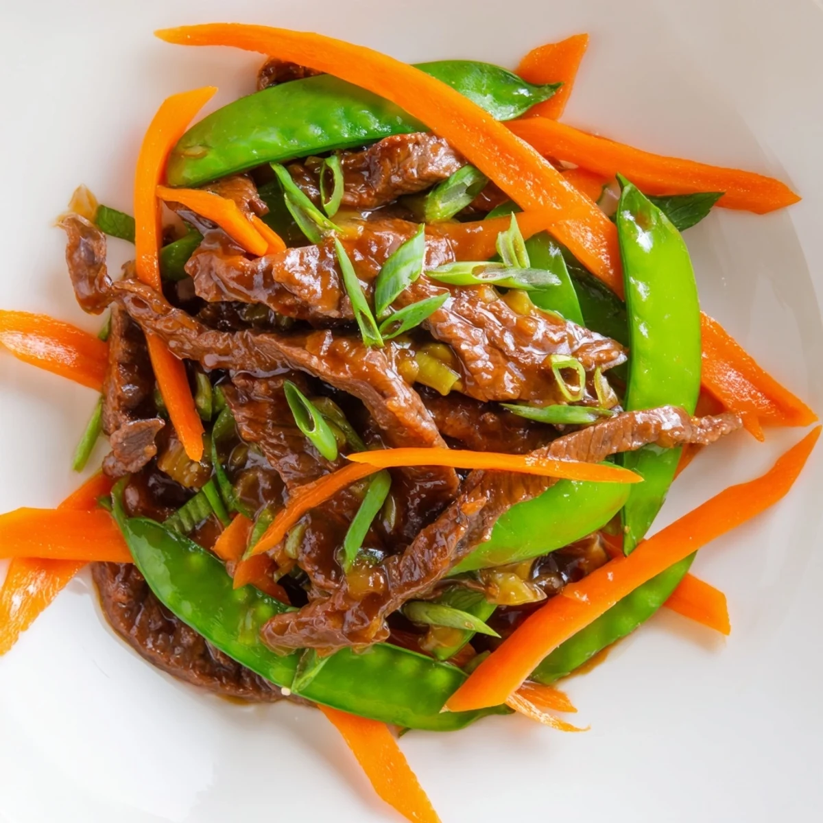 Tender beef stir fry with snow peas and carrots in glistening savory sauce, served with rice.