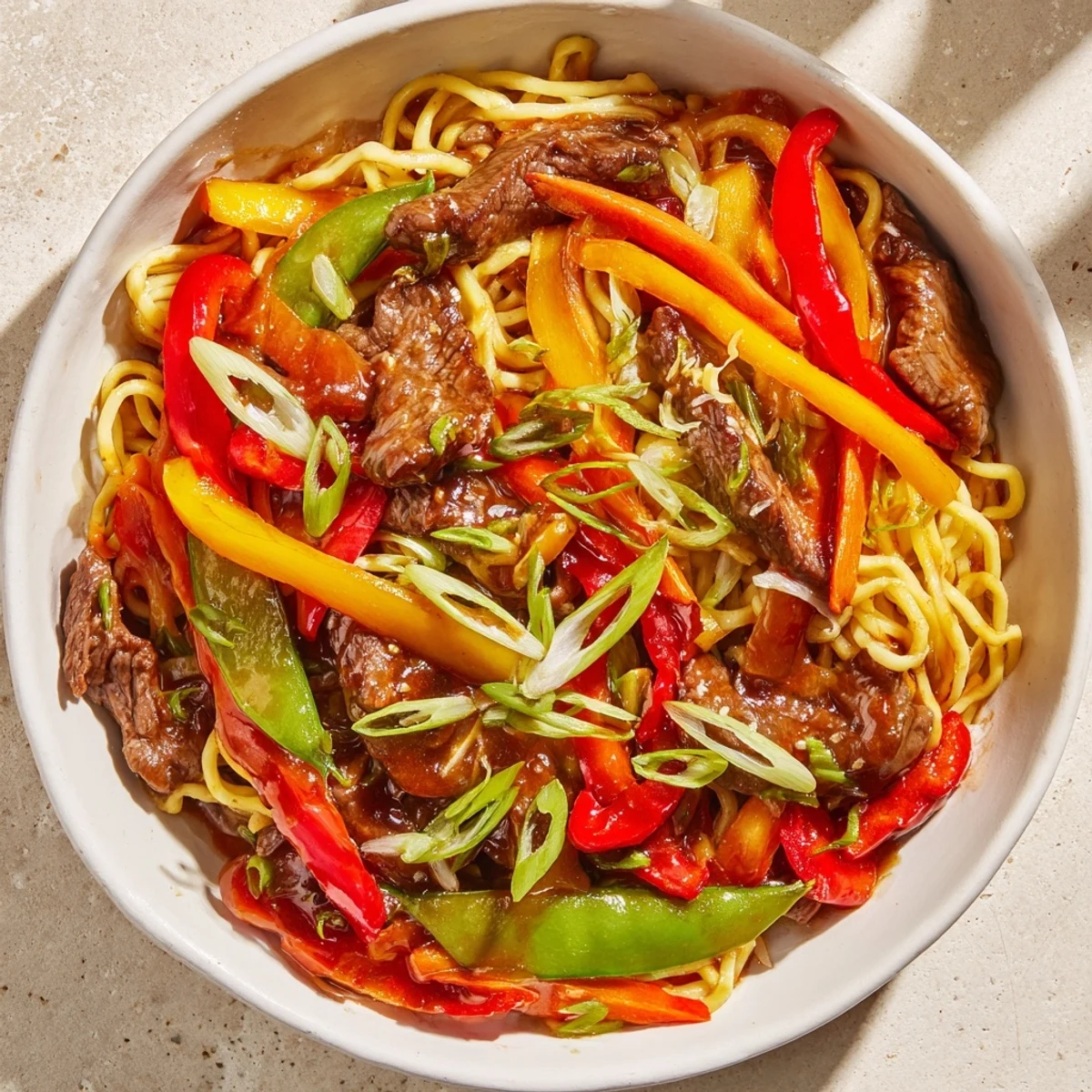 Steaming bowl of Spicy Beef Stir Fry with Noodles, glistening with savory sauce, ready to eat.