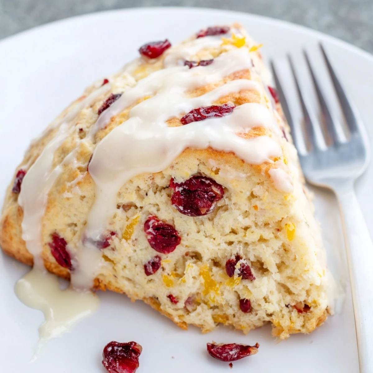 Freshly baked Cranberry and Orange Scones rest on a wire rack, featuring golden edges, visible orange zest, and ruby red cranberries.