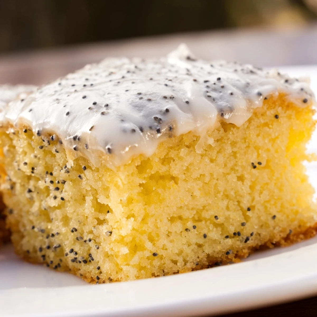 Overhead view of sliced Lemon Drizzle Traybake with Poppy Seeds, highlighting the tangy drizzle and delicate seed speckles.