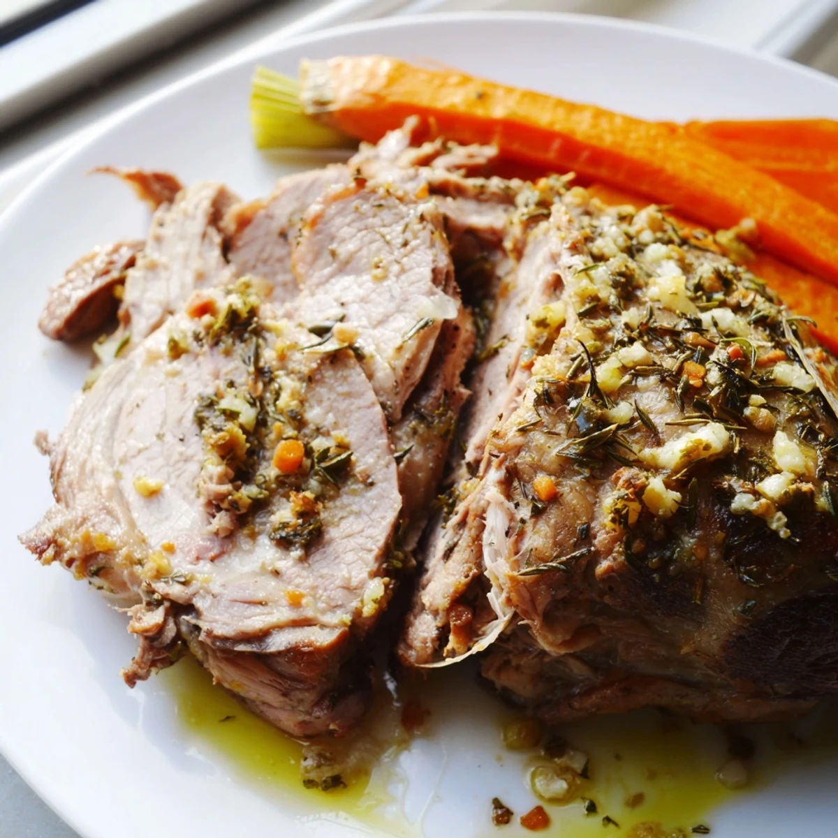 A golden, tender Garlic Herb Roasted Lamb Shoulder rests on a platter, surrounded by caramelized onions, carrots, and celery.