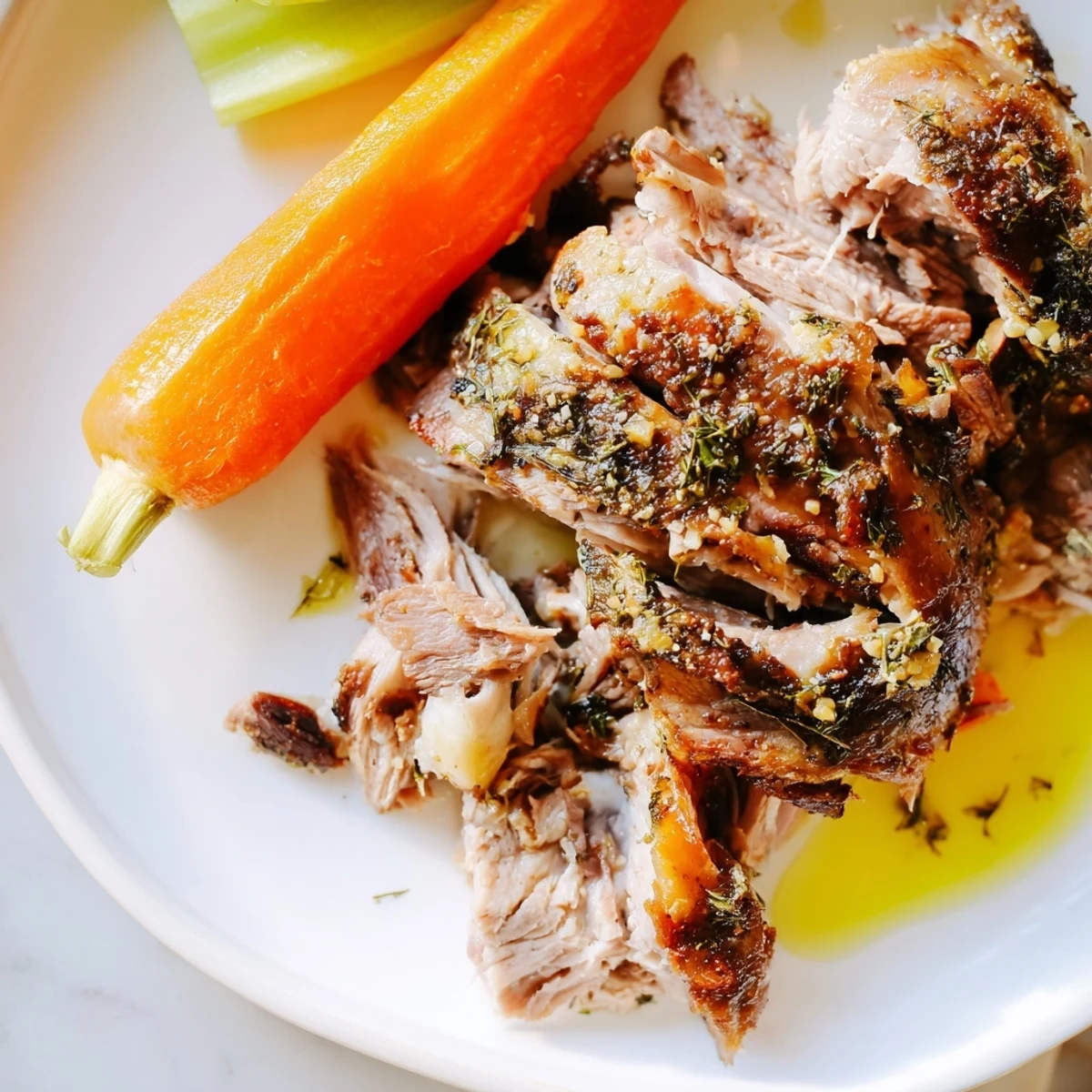 Fresh rosemary and thyme garnish this juicy Garlic Herb Roasted Lamb Shoulder, with roasted vegetables and pan juices nearby.