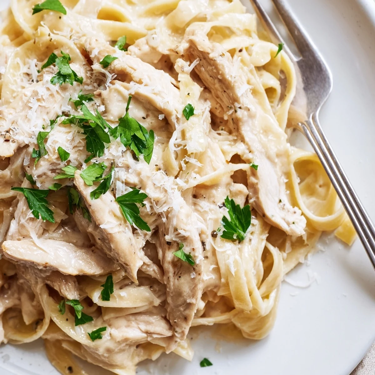 Close-up of Creamy Alfredo Pasta with Chicken, featuring golden chicken strips over fettuccine coated in rich Parmesan cream sauce.