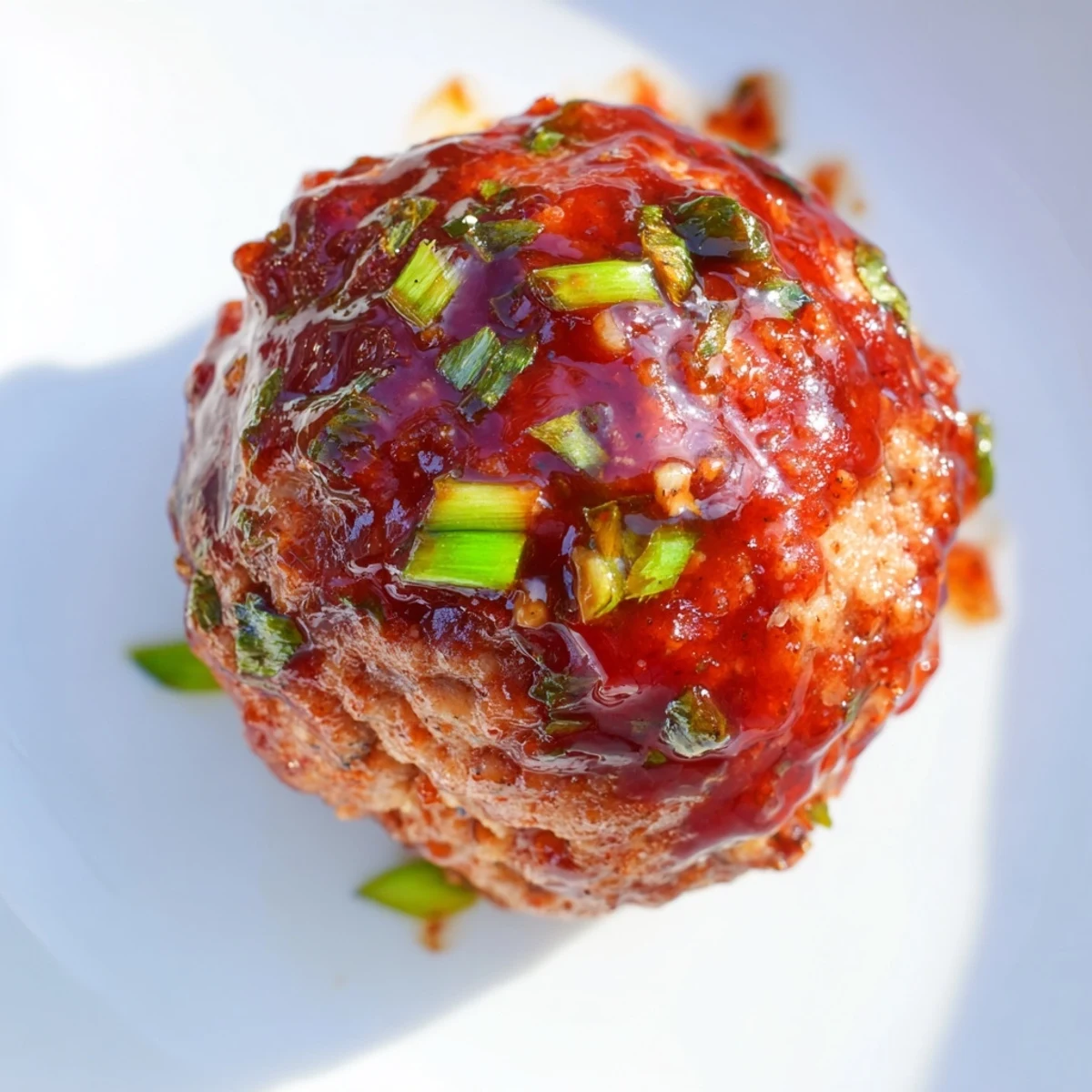 Close-up of tender turkey appetizer meatballs in a tangy-sweet glaze, garnished with chopped parsley and served warm.