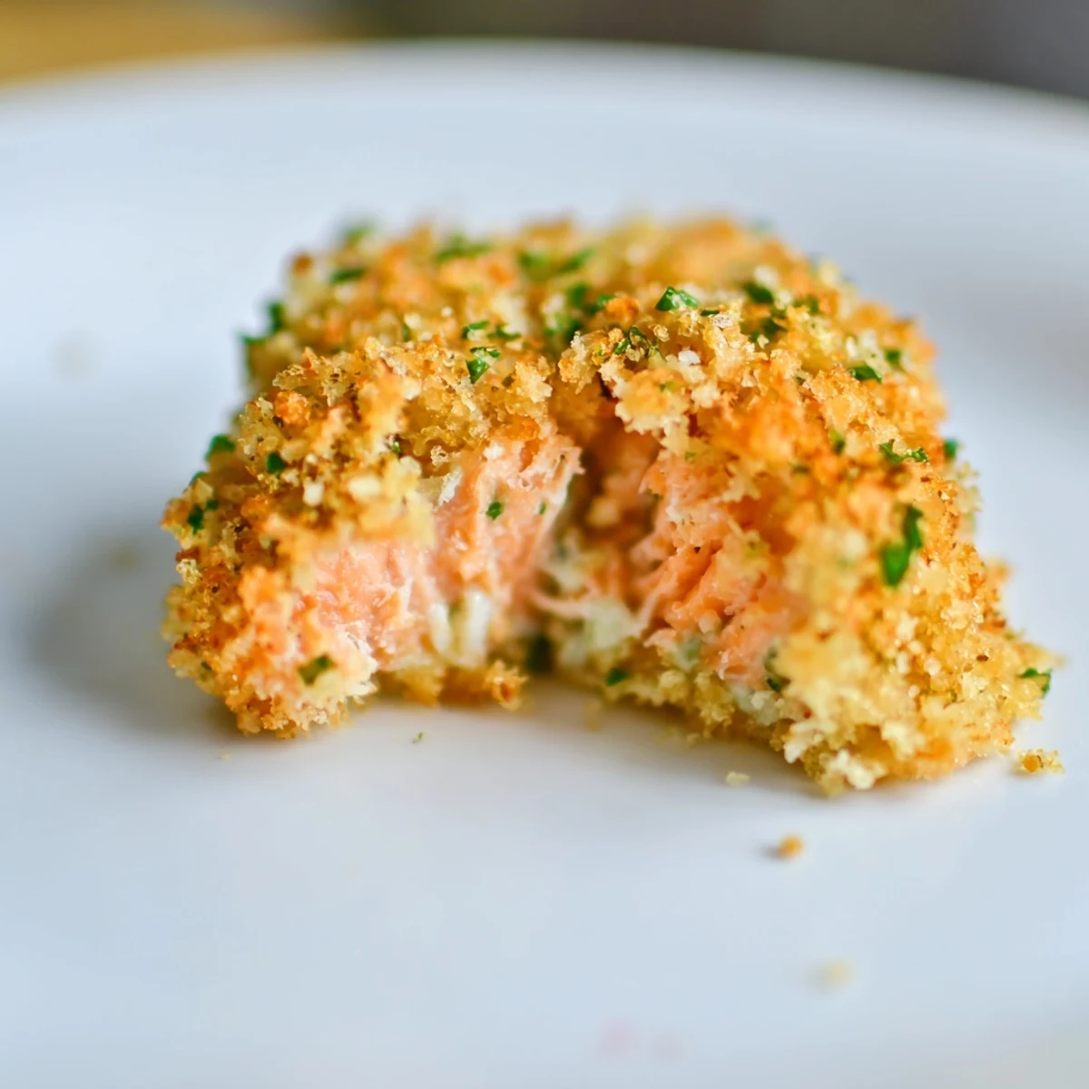 Crispy golden Baked Salmon Snack Bites arranged on a wooden board with lemon slices and herbs.