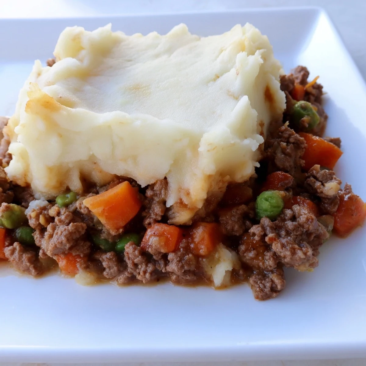Golden-brown Beef Shepherds Pie with Creamy Cauliflower Mash bubbling in a ceramic dish, served with a fresh green salad.