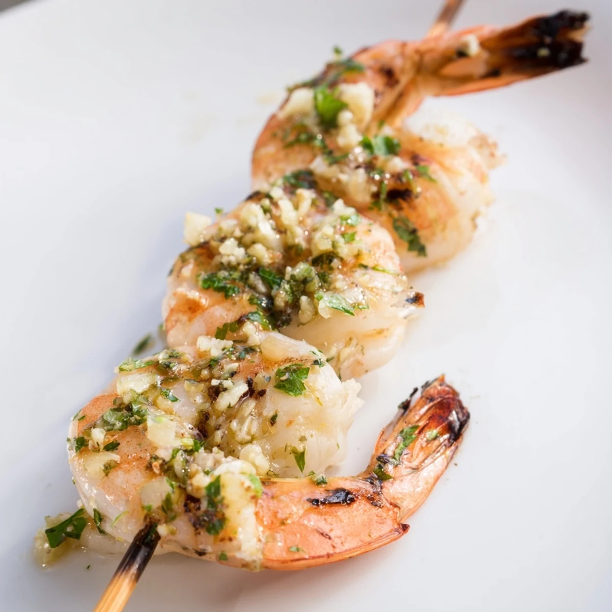Golden-brown Lemon Garlic Shrimp Skewers with Parsley are lined up on a grill with visible char marks.