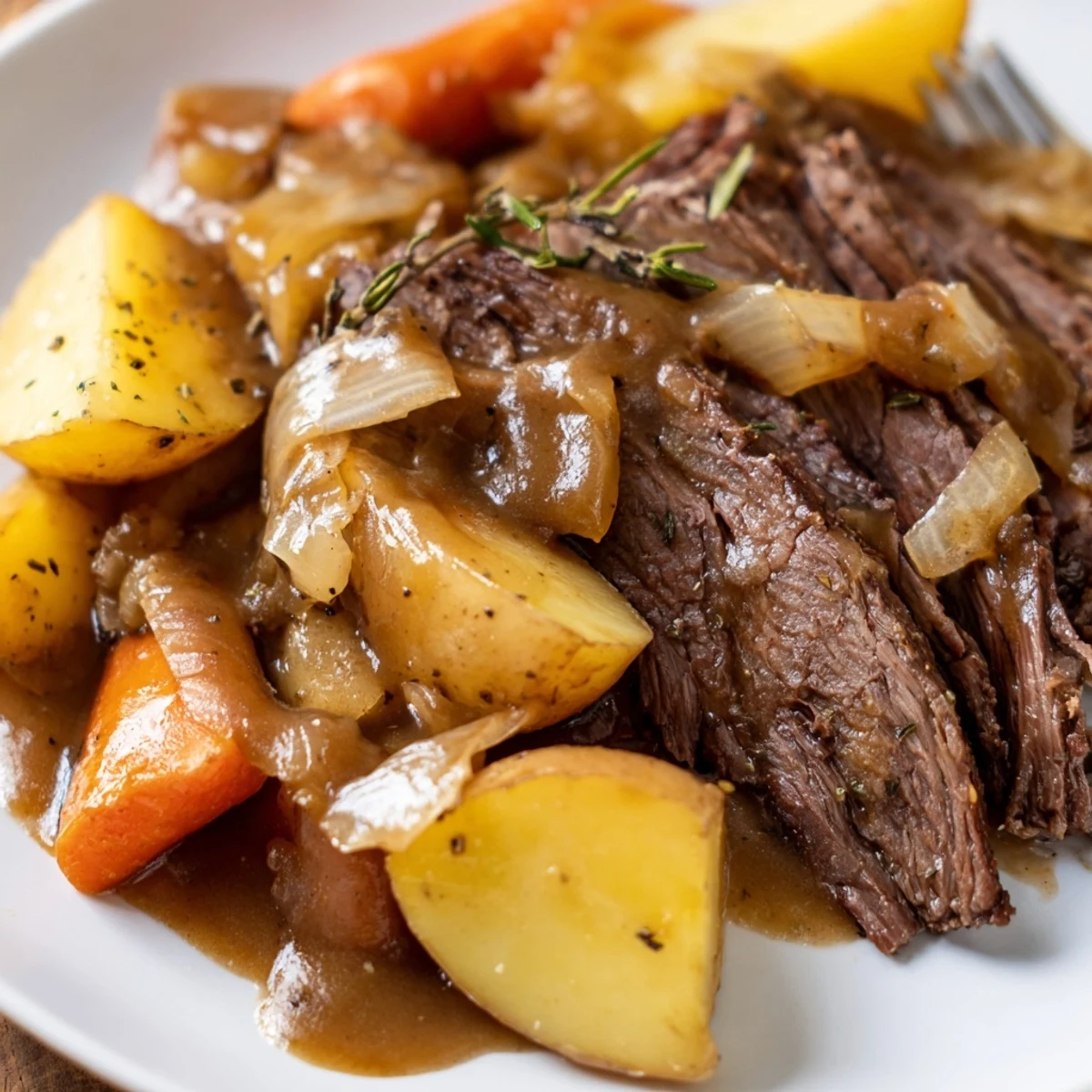 Tender Slow Cooker Pot Roast with Carrots and Potatoes, served on a platter with rich, glossy gravy poured over the top.