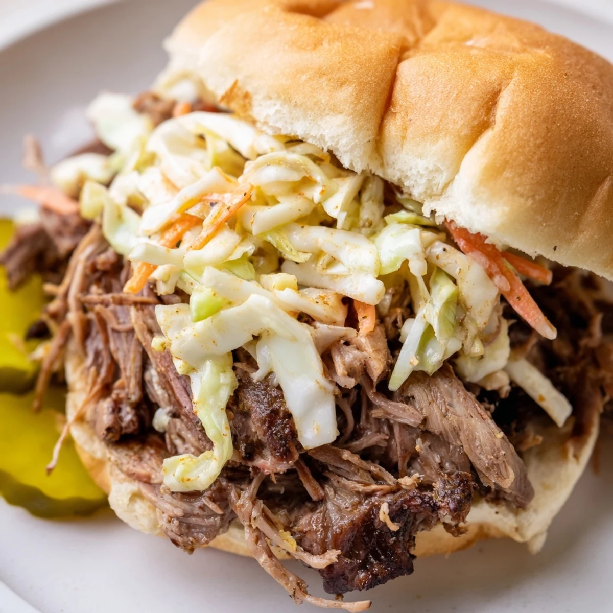Fork-tender Slow Cooked Pulled Beef Sandwiches piled high on a toasted bun, ready to serve with tangy coleslaw.