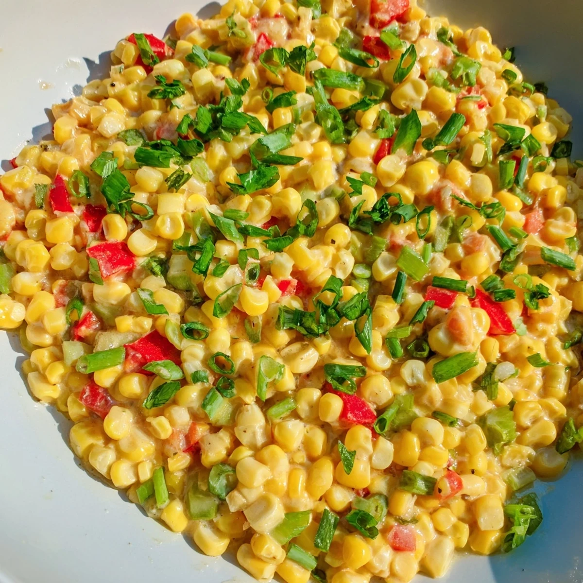 Close-up of Creole Corn Maque Choux showcasing glossy cream sauce, diced tomatoes, and fresh parsley garnish for a classic Southern side dish.