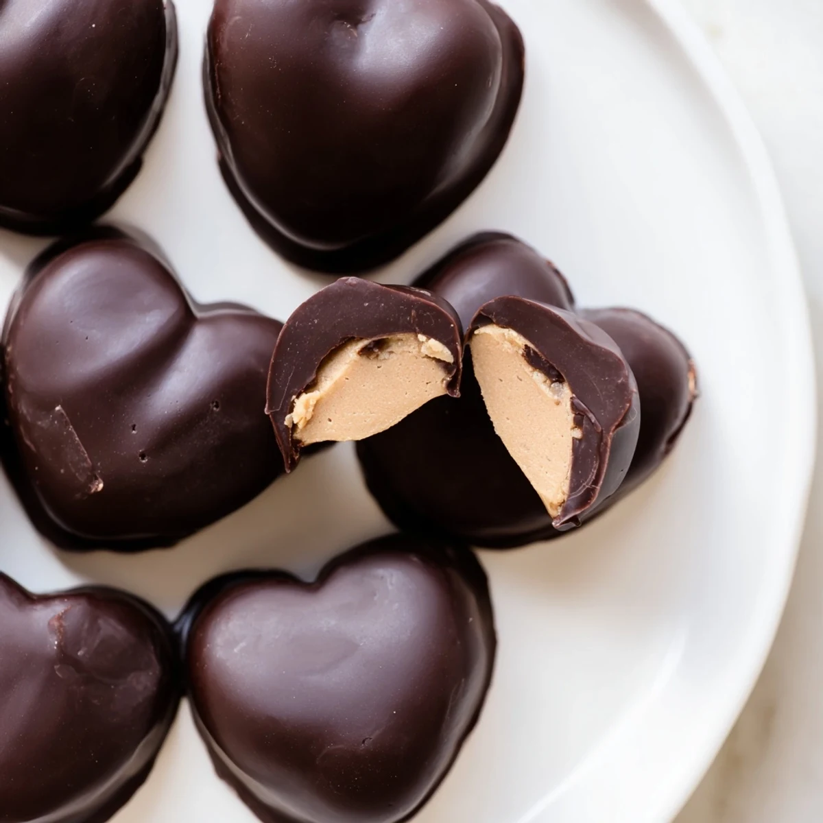 A close-up of rich chocolate peanut butter hearts, showcasing the creamy peanut butter filling inside a decadent dark chocolate shell.