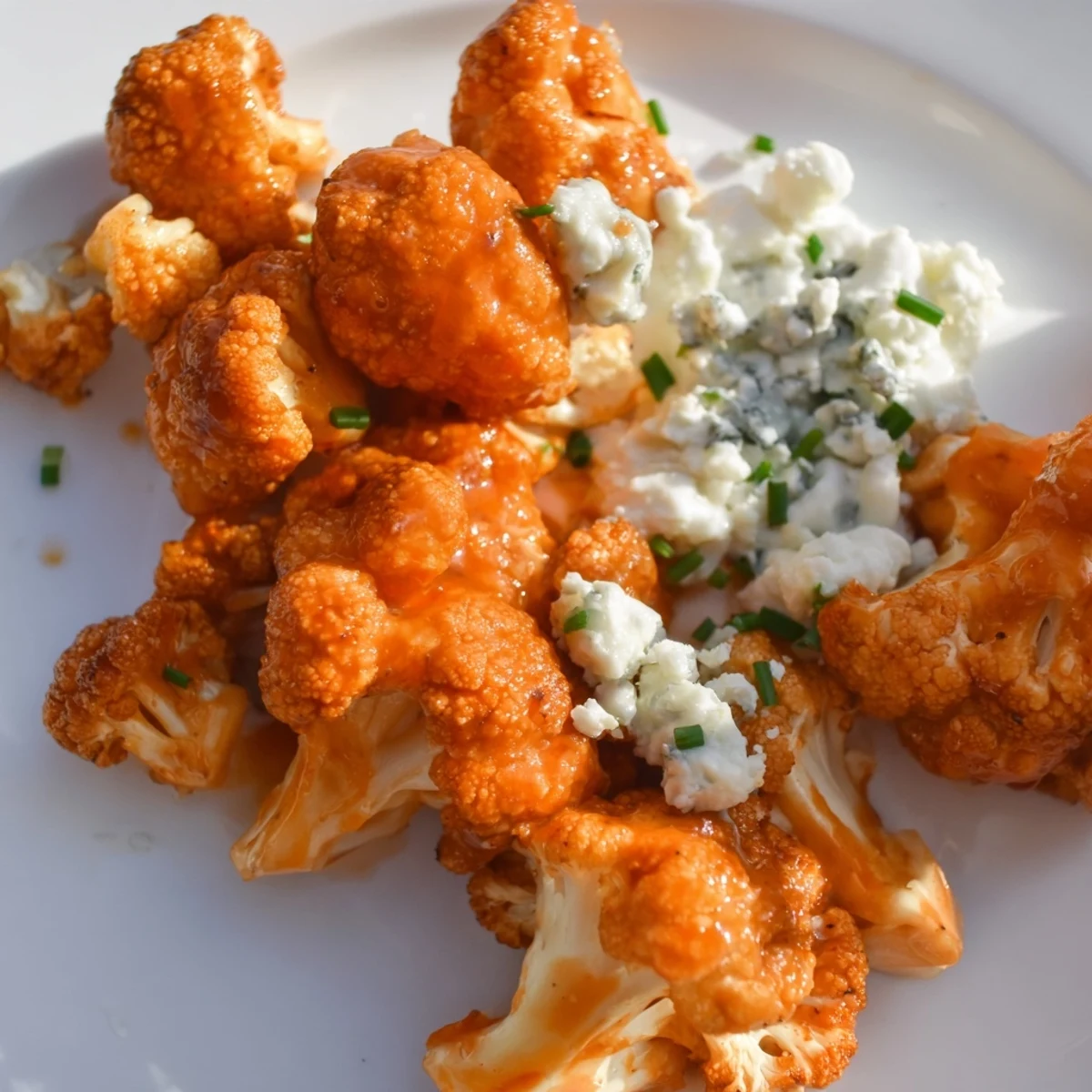 Crispy baked Buffalo Cauliflower Wings with Blue Cheese dip are served on a rustic board, offering a spicy and savory vegetarian alternative to traditional wings.