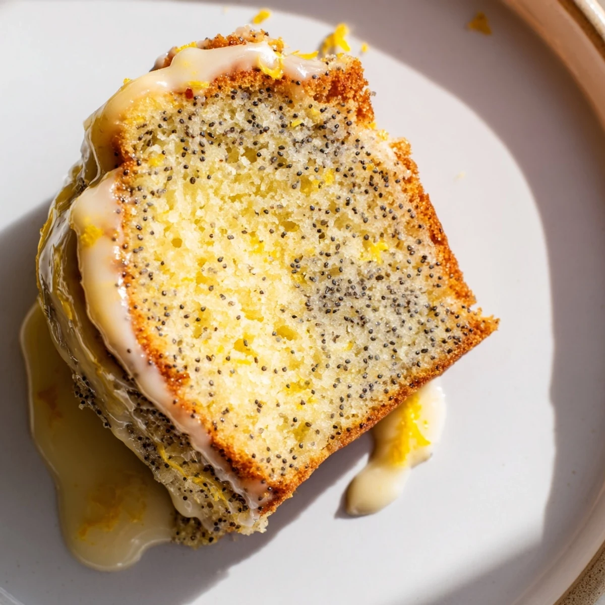 Overhead view of a golden-brown Lemon Poppy Seed Bundt Cake with a sugary lemon glaze, perfect for spring tea parties or Easter brunch.