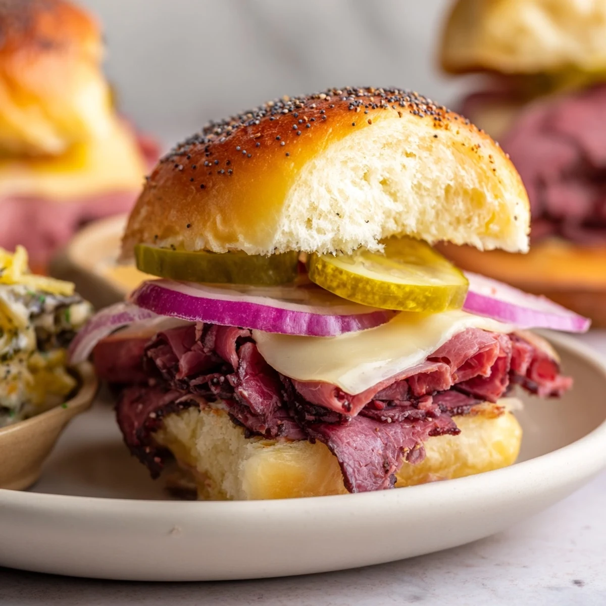 Golden Corned Beef Sliders with Mustard and Swiss cheese melt together on soft buns, garnished with red onion and pickles.