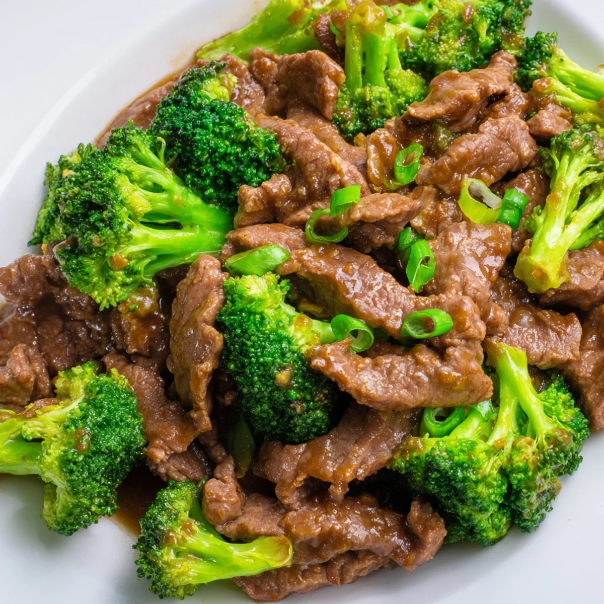 Sizzling Beef and Broccoli Stir Fry with Ginger Sauce in a wok, garnished with green onions, ready to serve with noodles.