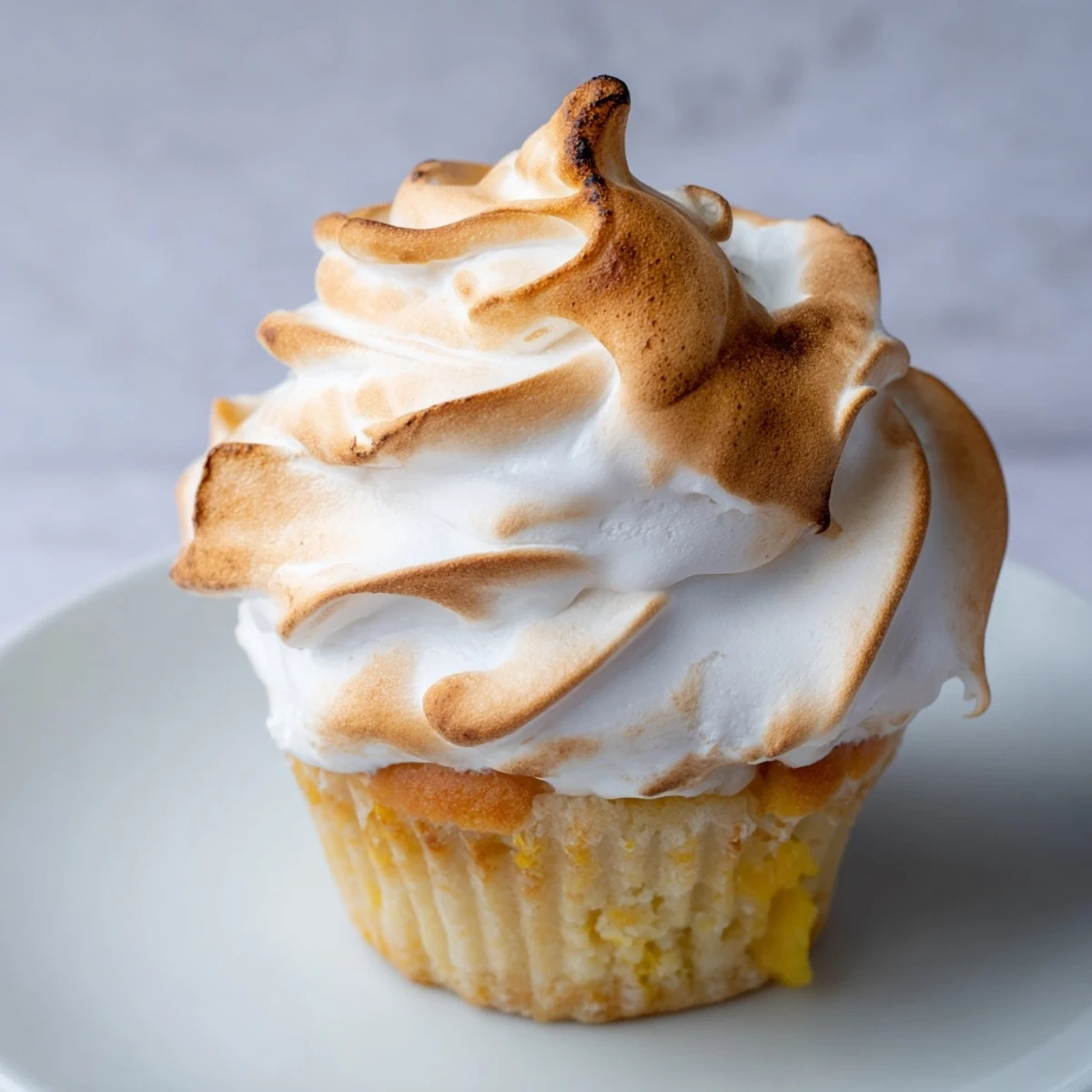 A close-up of Lemon Meringue Cupcakes showing golden toasted meringue peaks on fluffy white frosting.
