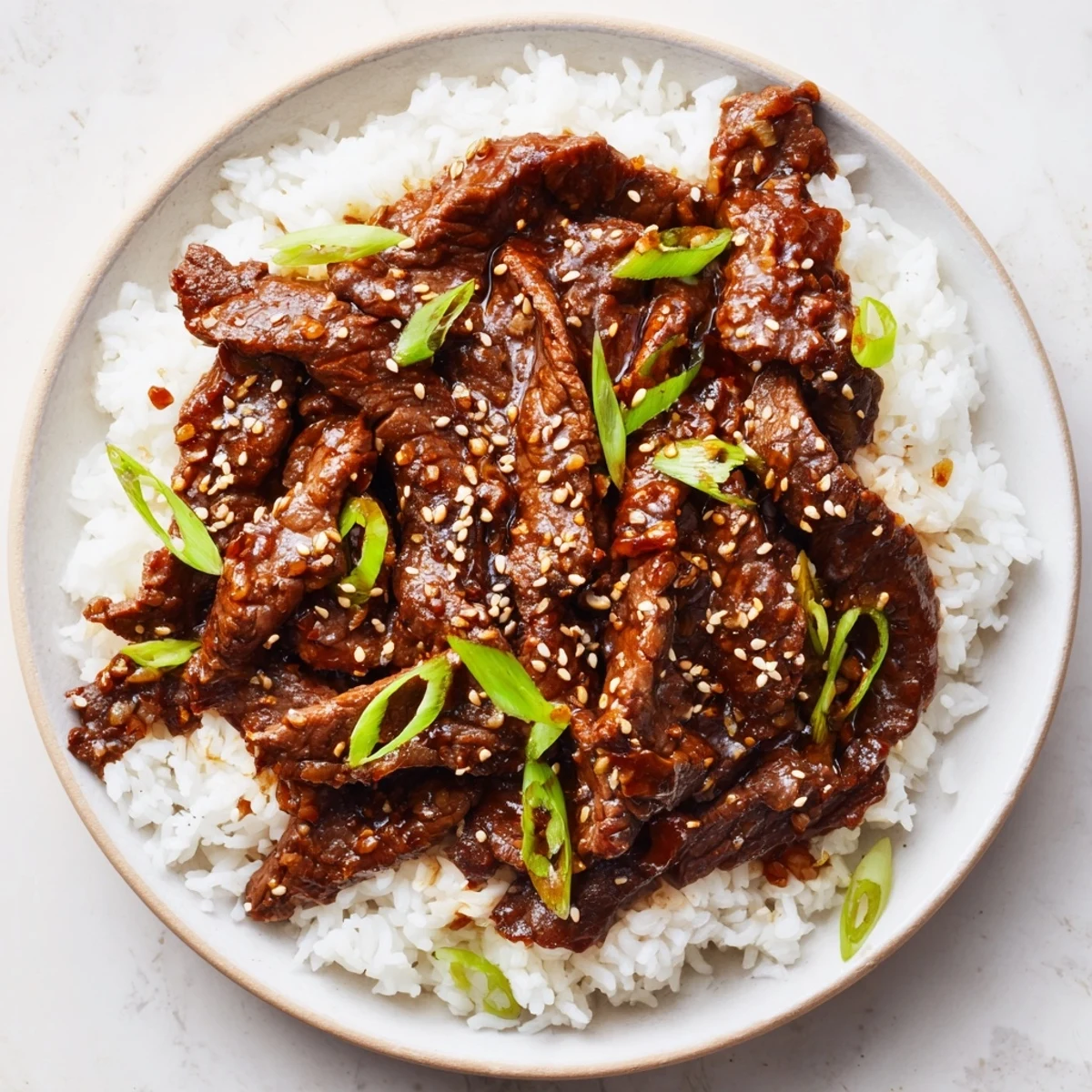 Tender slices of beef simmer in a savory-sweet sauce in this Ultimate Slow Cooker Mongolian Beef, served over fluffy steamed rice.