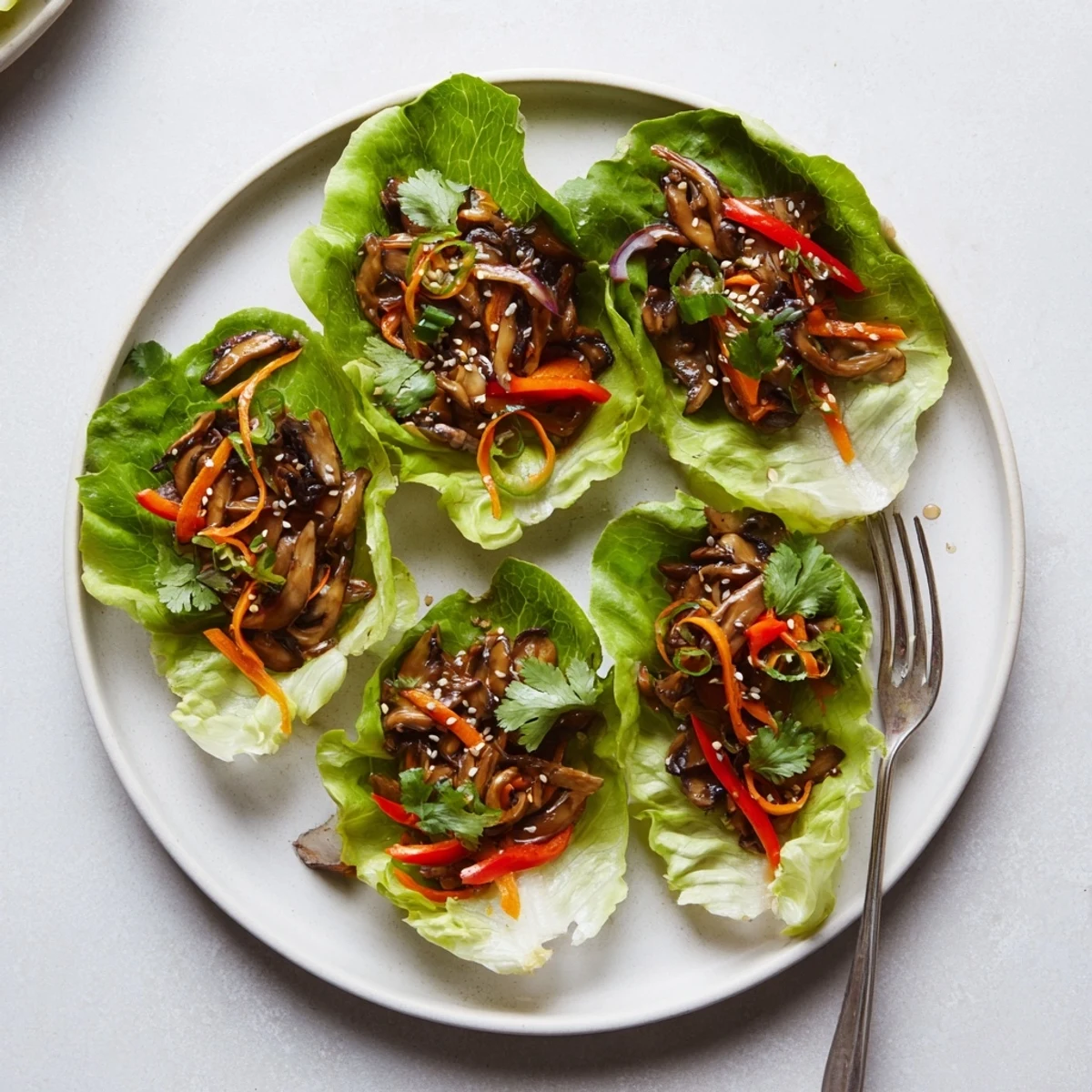 Vibrant Shiitake Mushroom Lettuce Wraps filled with savory sautéed mushrooms and crisp veggies on a white plate.