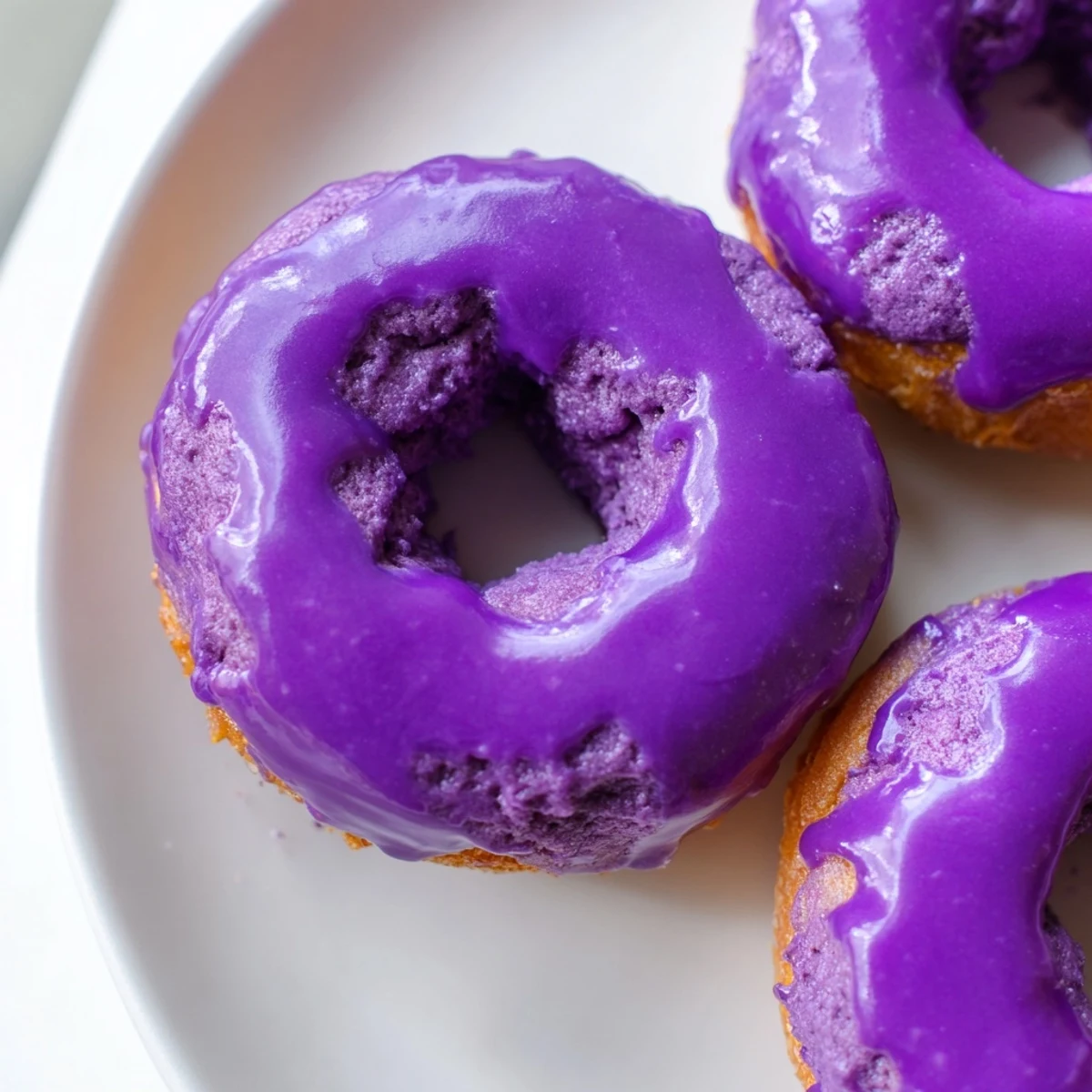 A close-up of bite-sized Ube Mochi Donuts with a glossy ube glaze, perfect for a sweet Filipino-Japanese dessert.