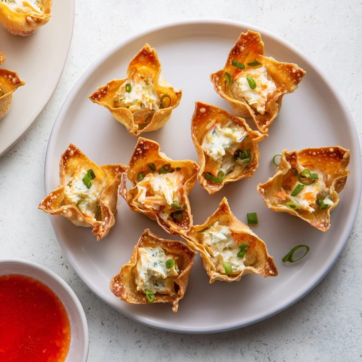 Golden-brown Crispy Crab Rangoon Bombs with Creamy Filling are served warm on a plate with sweet chili dipping sauce.