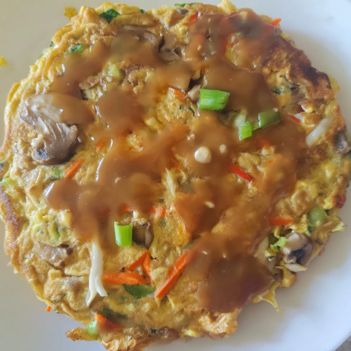 Fluffy vegetable-packed Egg Foo Young omelet fried until golden with savory gravy sauce topping