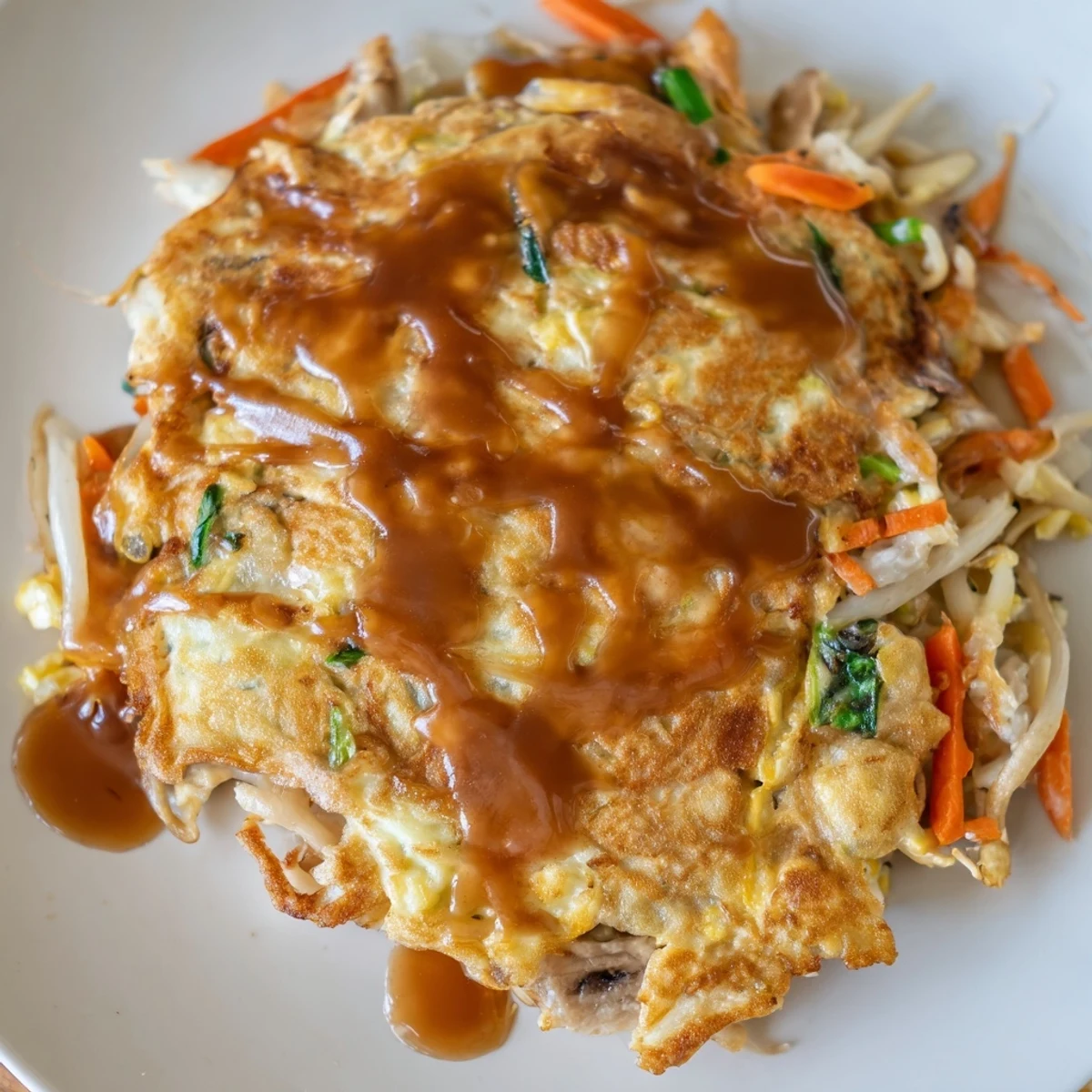 Chinese-style Egg Foo Young served hot over steamed white rice with generous gravy pour
