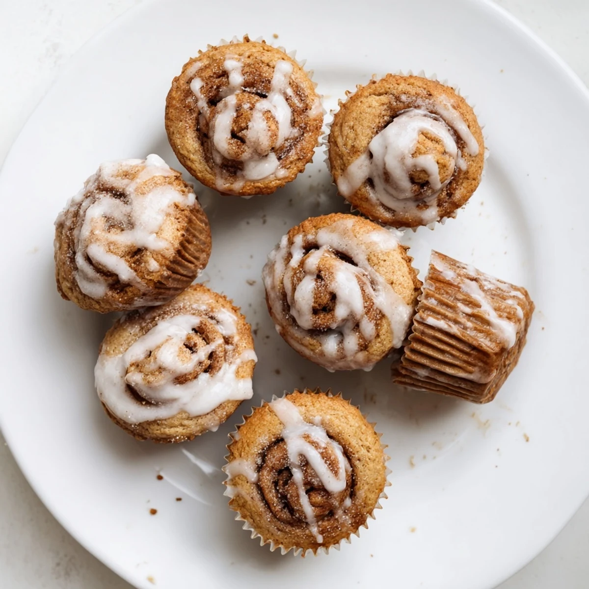 Golden cinnamon roll protein muffins topped with sweet white icing on a wire cooling rack