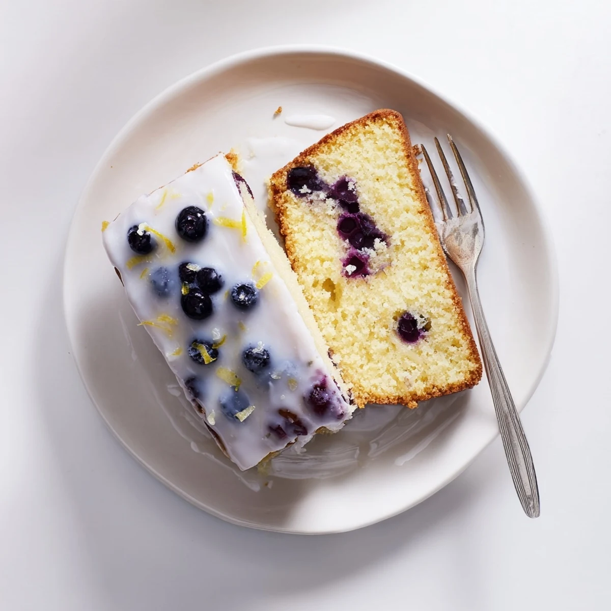 Golden lemon blueberry cake drizzled with tangy glaze and fresh blueberry garnish