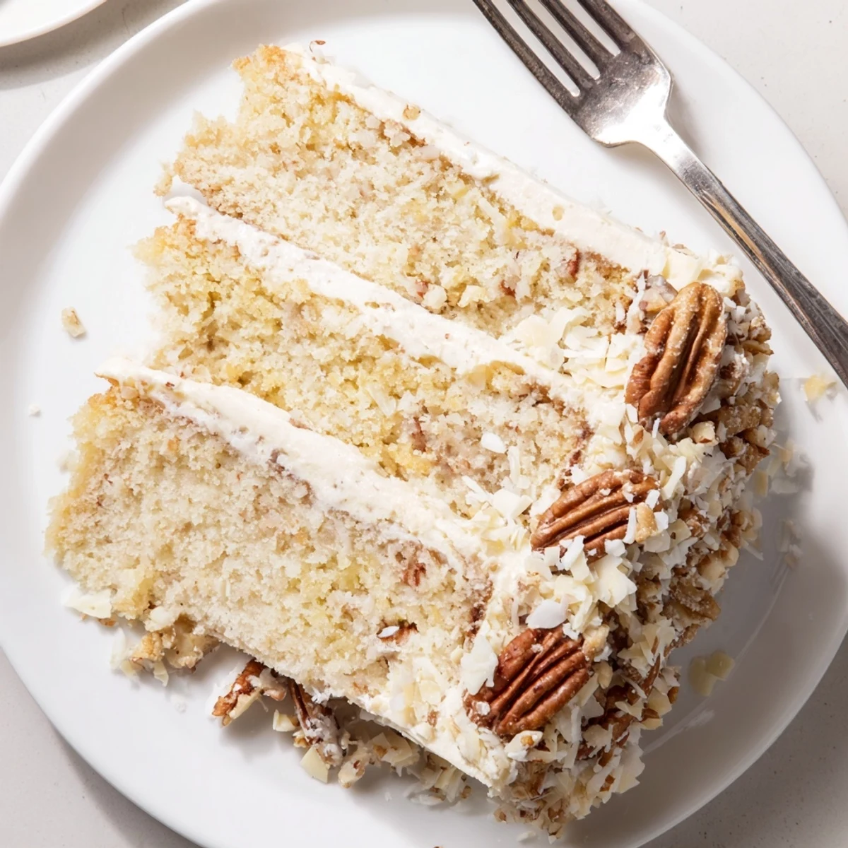 Three-tier White German Chocolate Cake stacked high with golden coconut pecan filling visible between moist white layers.