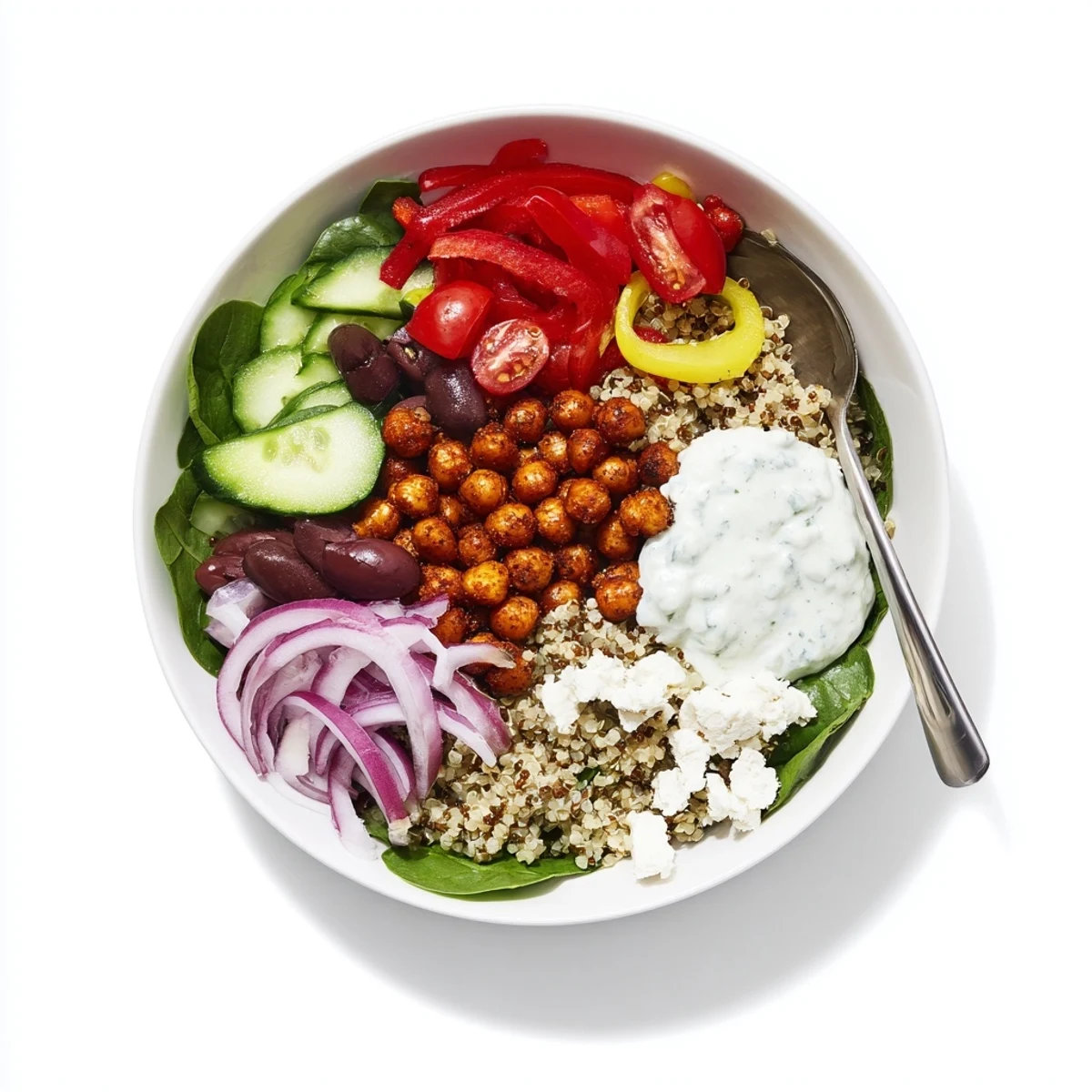 Healthy Greek power bowl featuring roasted chickpeas, crisp veggies, quinoa base, and tangy tzatziki topping