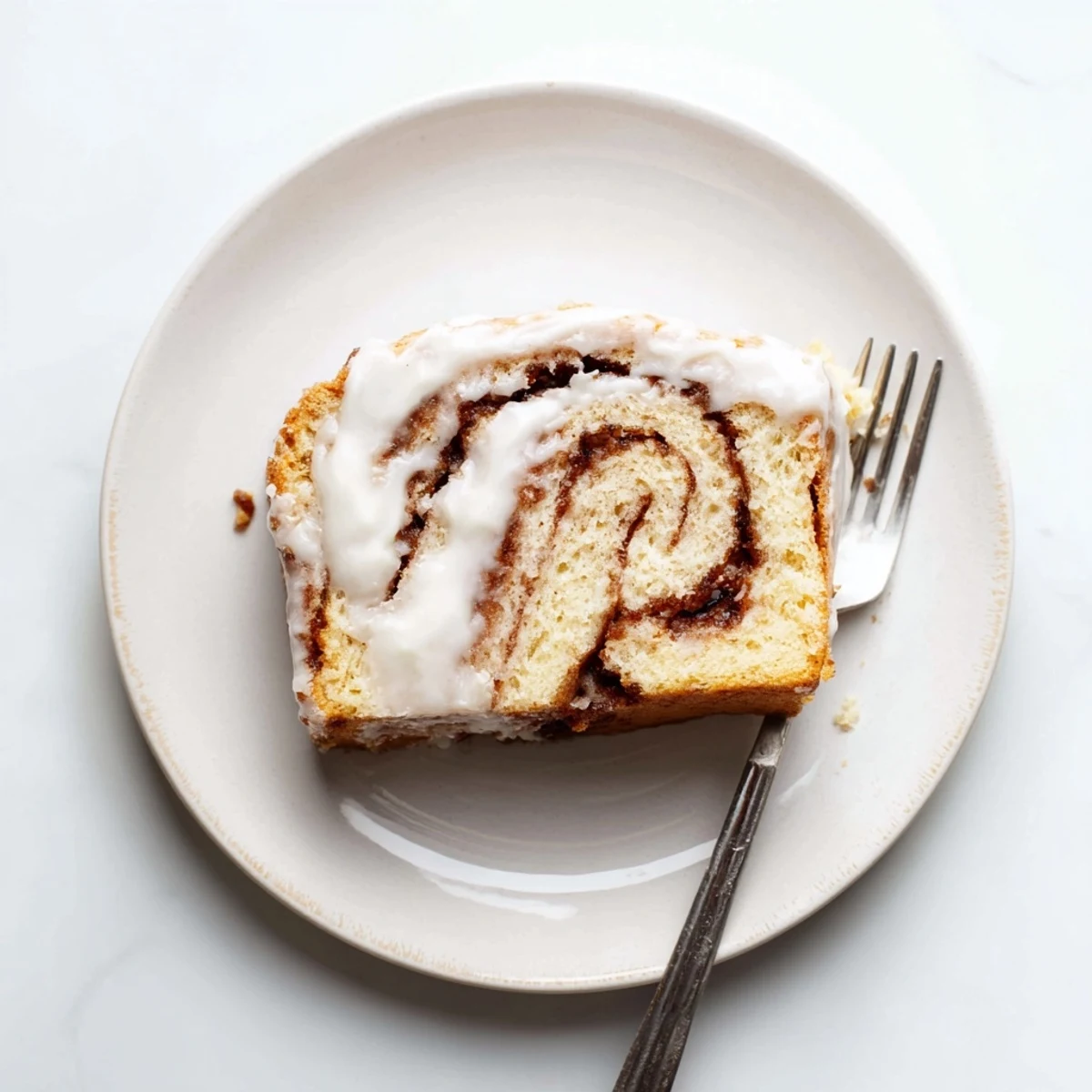 Golden cinnamon roll cake with buttery sugar swirls and creamy vanilla glaze drizzled over the top