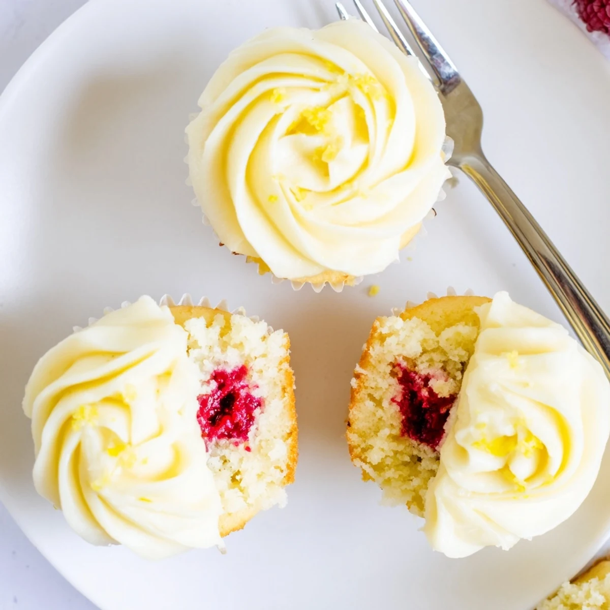 Golden moist lemon cupcakes with hidden raspberry filling topped with fluffy lemon buttercream frosting