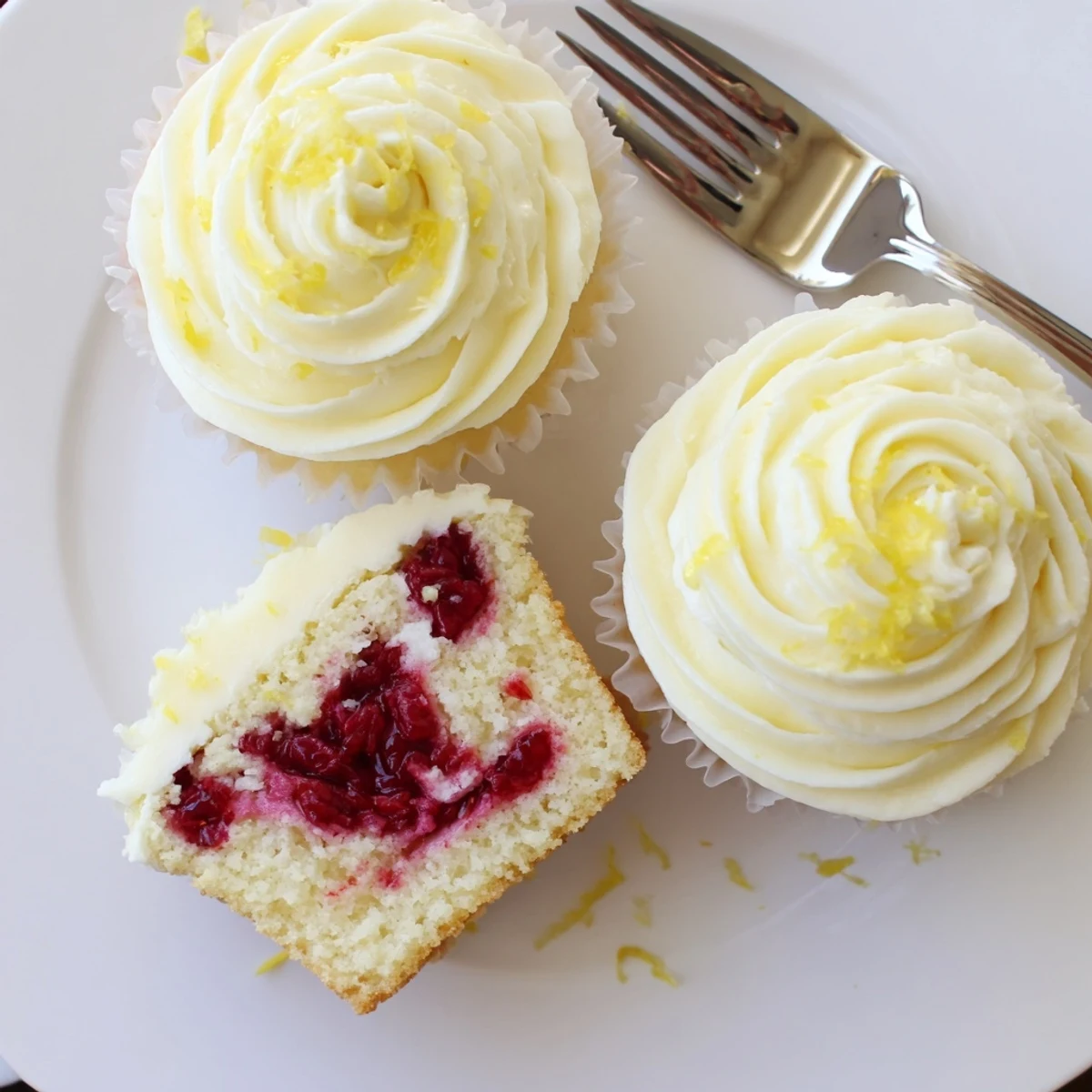 Zesty lemon raspberry cupcakes with tangy fruit center and smooth lemon frosting on top