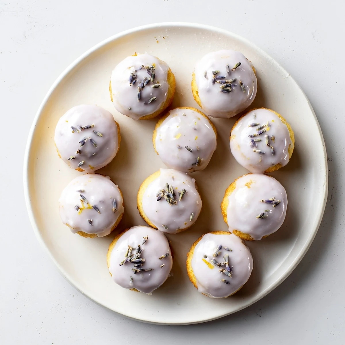 Delicate lemon mini cakes with purple lavender glaze served on a rustic wooden board for afternoon tea