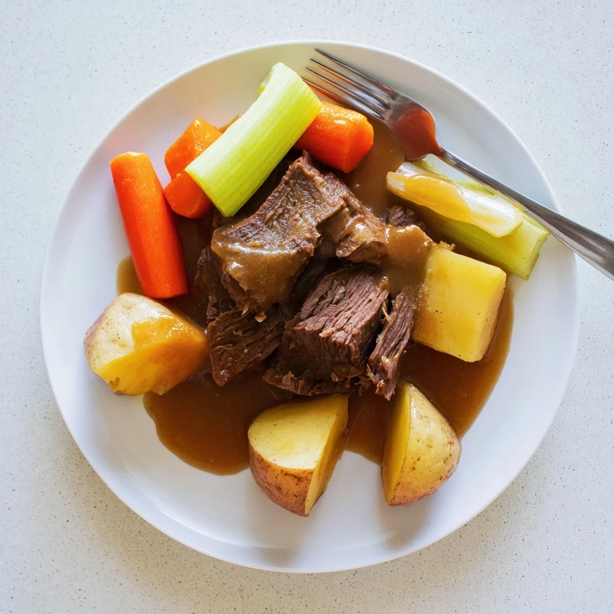 Golden brown Southern style pot roast with tender carrots, potatoes, and rich brown gravy ladled over the sliced beef.