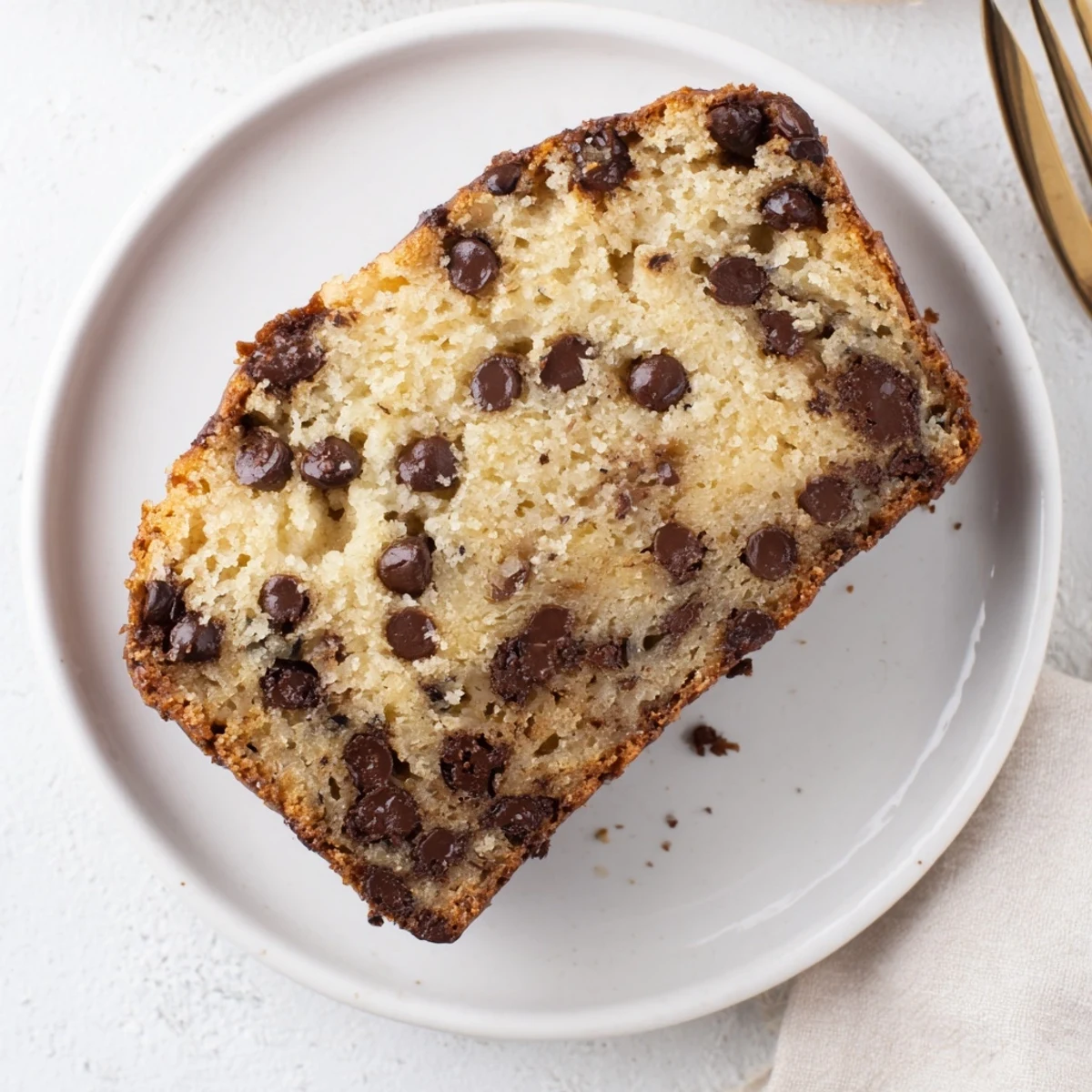 Golden brown chocolate chip banana bread loaf with melted chocolate chunks on top