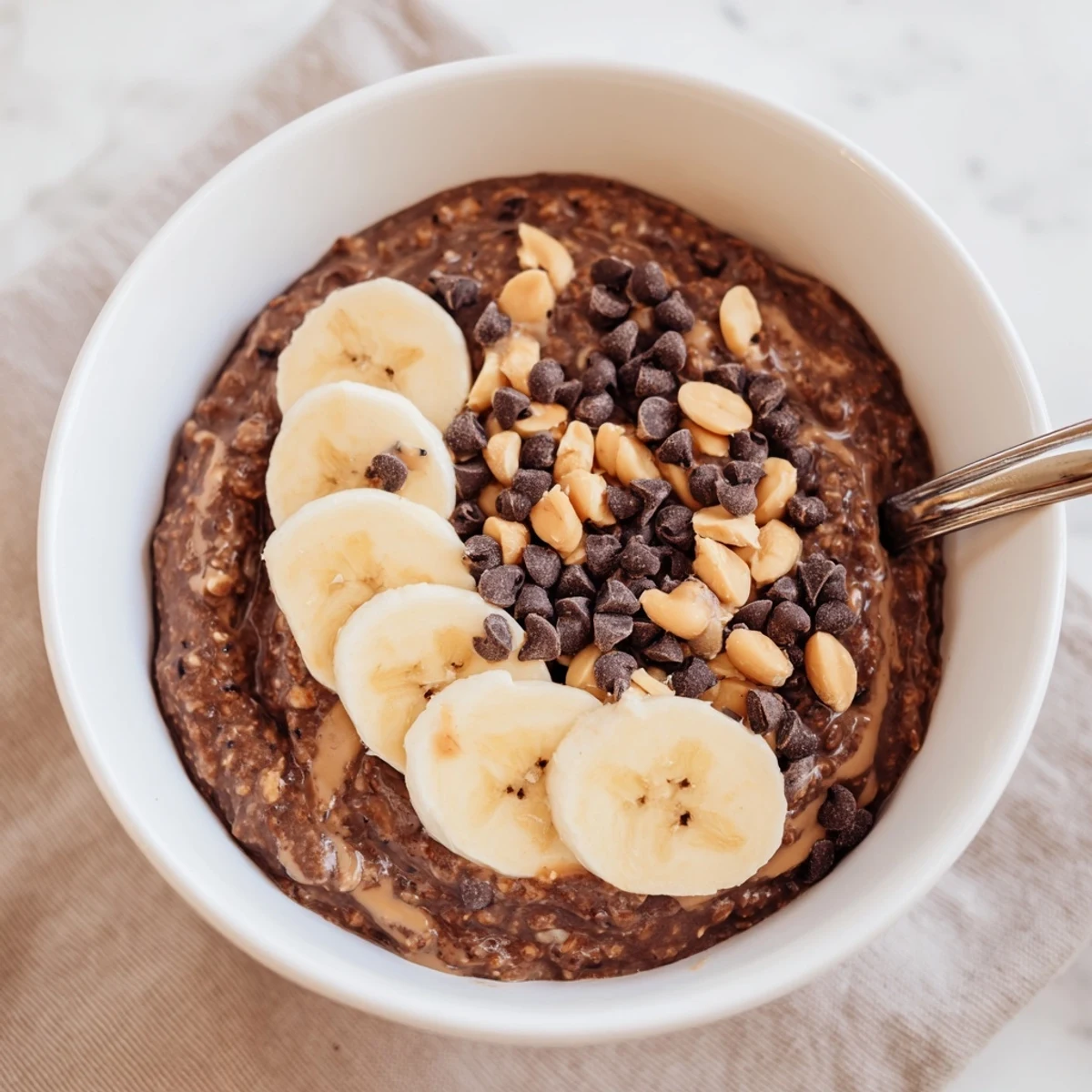 Thick chocolate peanut butter overnight oats served chilled with chopped peanuts and banana
