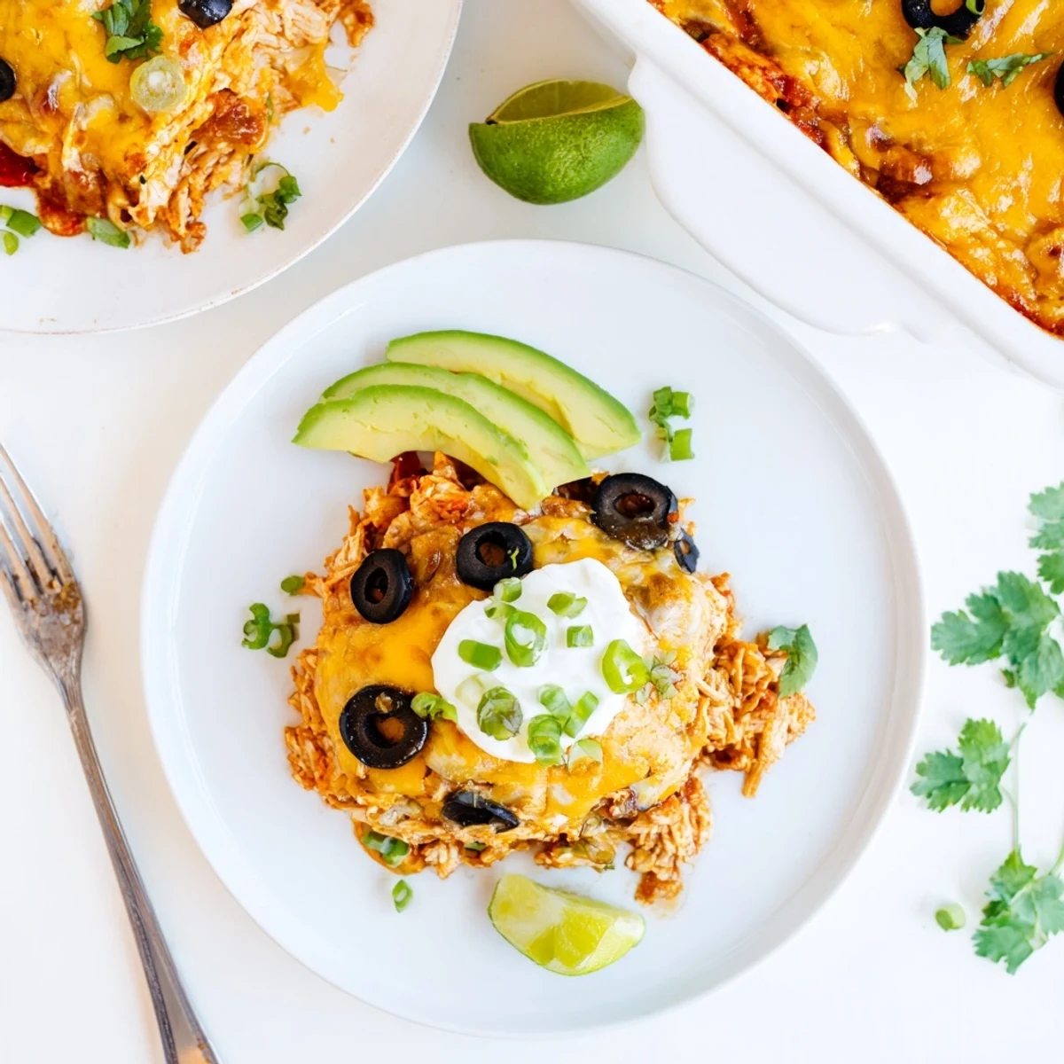 Cheesy shredded chicken enchilada bake bubbling with sauce in a glass casserole dish