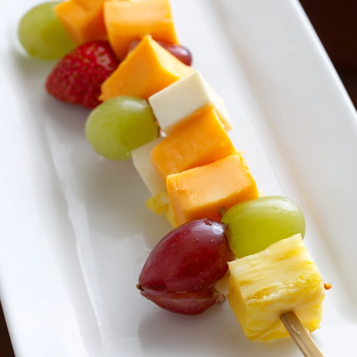 Fresh fruit and cheese kabobs featuring strawberries, grapes, and creamy Monterey Jack on wooden skewers