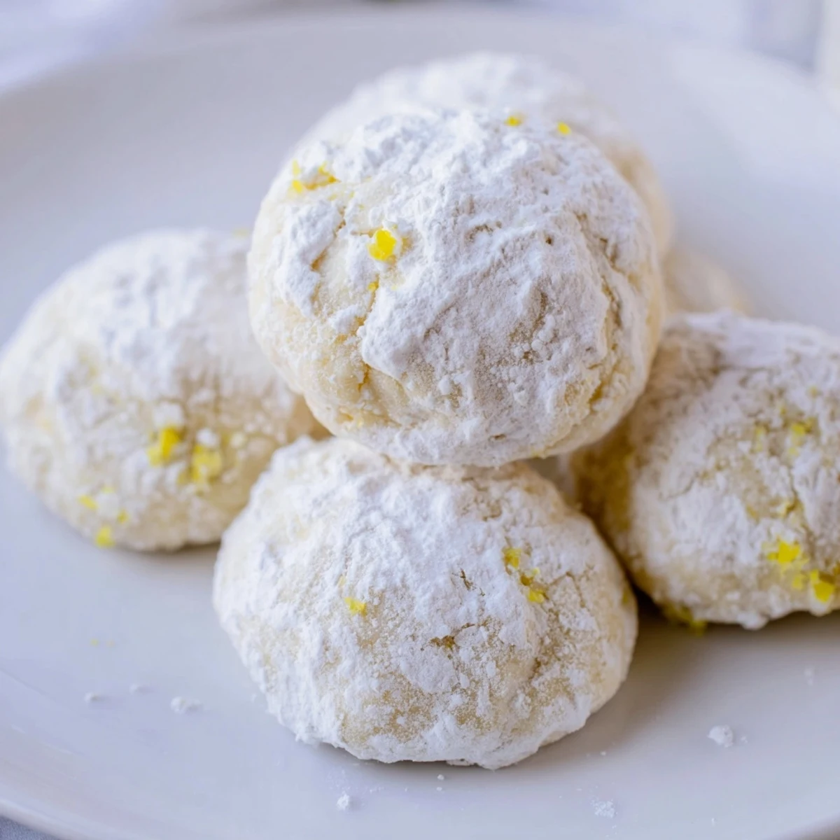 Powdered sugar-coated lemon meltaways arranged on a rustic white serving plate
