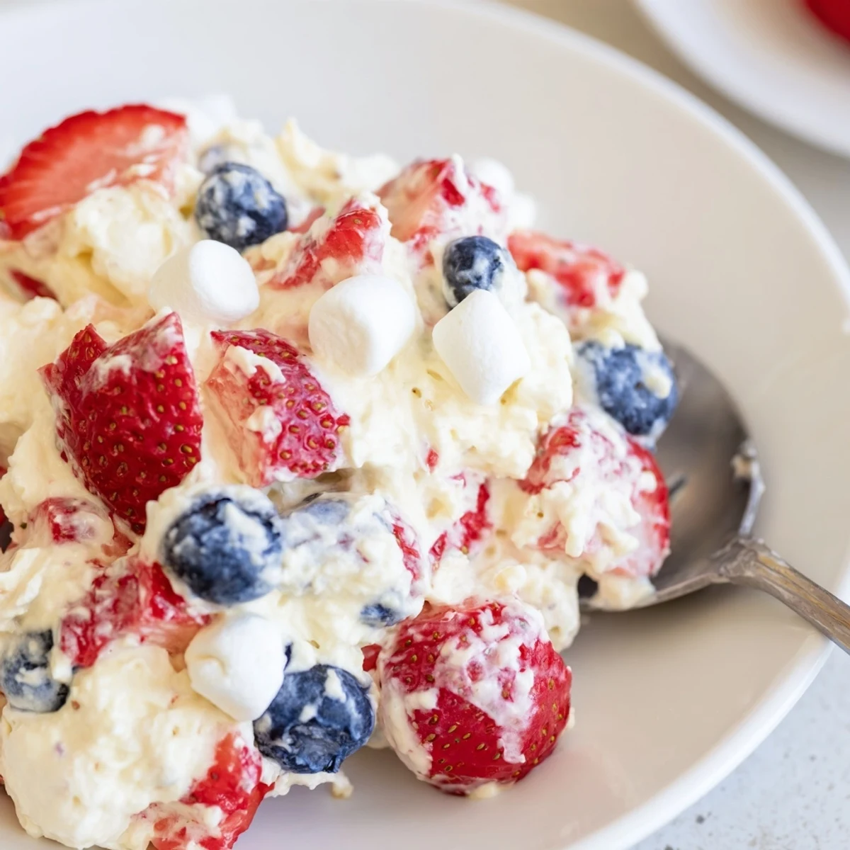 Vibrant Red White Blue Cheesecake Salad with fluffy marshmallows and ripe berries in a glass dish