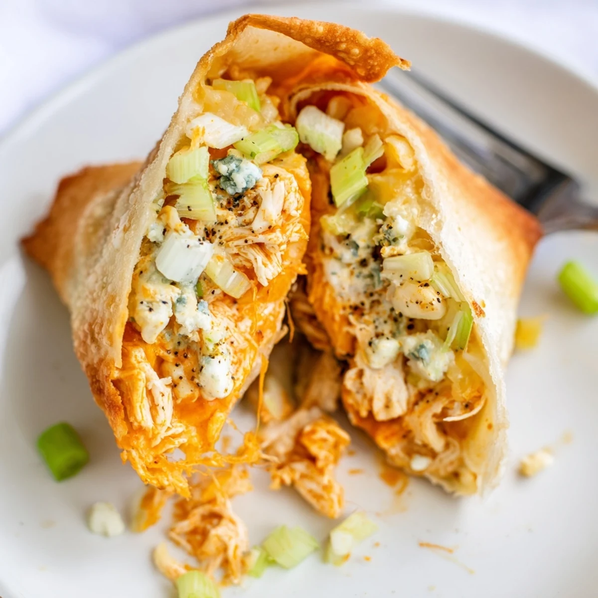Hot Buffalo Chicken Egg Rolls resting on paper towels, celery and blue cheese