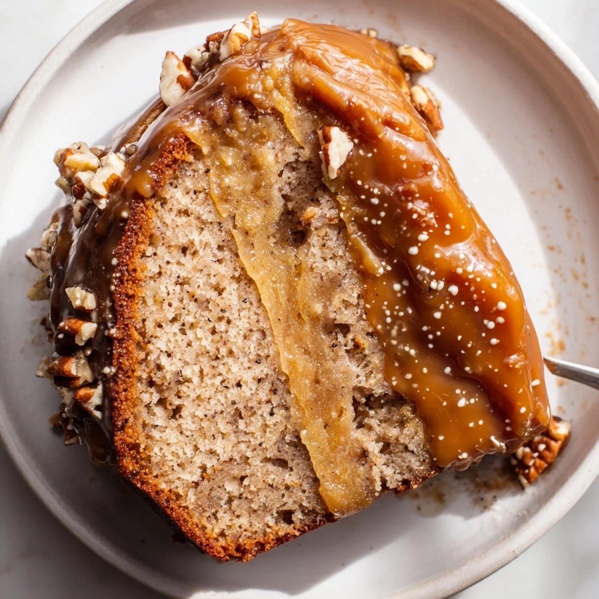 Decadent Salted Caramel Brown Butter Banana Cake topped with toasted pecans