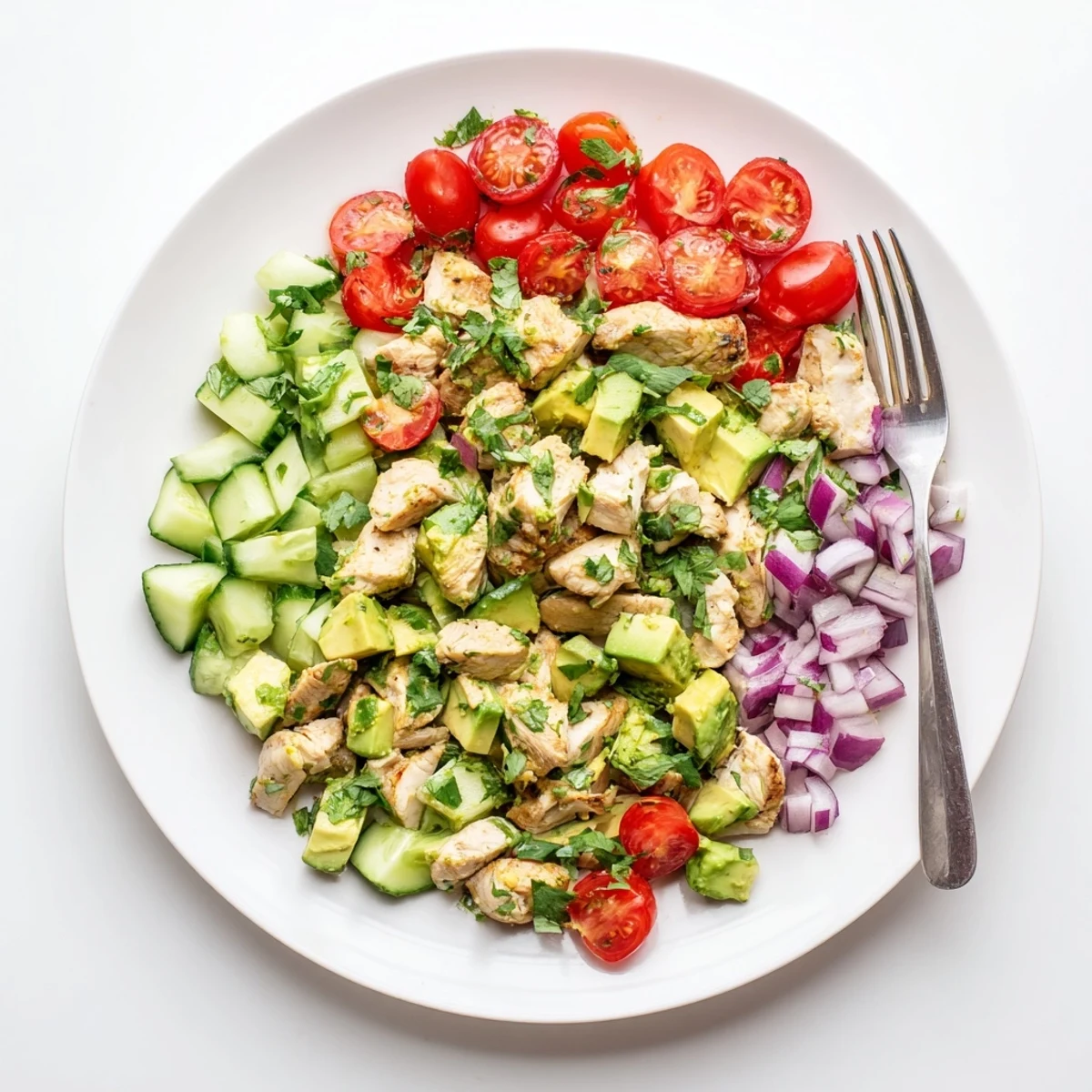 Fresh healthy avocado chicken salad served in a white bowl featuring tender diced chicken breast, creamy ripe avocado pieces, crisp vegetables, and bright herbs drizzled with tangy lime olive oil dressing