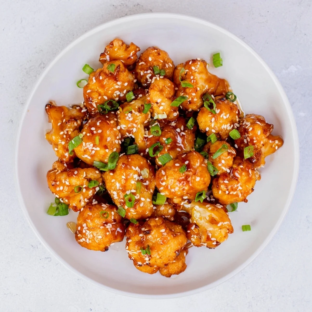 Golden brown sticky honey garlic cauliflower glistening with sweet savory glaze and sesame seeds